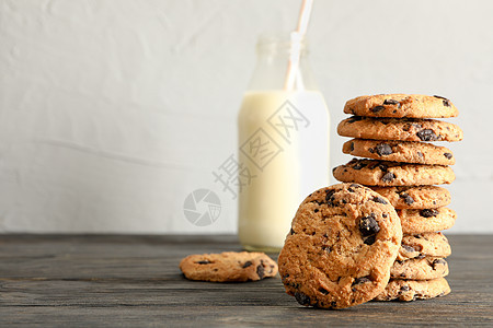 木制桌上的巧克力饼饼干和牛奶瓶 体味巧克力曲奇饼和奶粉图片