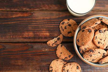 最顶视图木制桌上的巧克力饼干和牛奶杯 品尝巧克力曲奇饼和奶粉图片