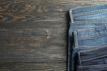 不同的牛仔裤折叠在木制背景 文字空间上购物口袋棉布蓝色桌子男朋友裤子公司男人条纹背景图片