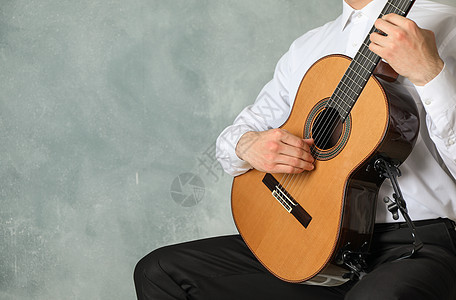 男人玩经典吉他 在光背景 文字空间的轻背景下音乐爱好演员指甲艺术玩家吉他手音乐会父亲歌曲图片