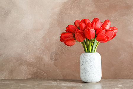 在棕色背景 文字空间的桌子上挂着美丽的红色郁金香图片