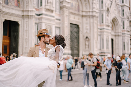 多种族结婚夫妇 意大利佛罗伦萨的婚礼 高加索新郎圈子和杜奥莫广场的非裔美籍新娘亲吻图片
