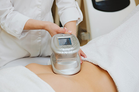 近距离接近美容学家 用特别仪器按摩女性腹部的乳房皮肤控制技术程序电子美容师化妆品医疗温泉沙龙图片