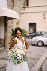 在意大利佛罗伦萨举行的婚礼 穿着白色连衣裙和长面纱的非洲裔美国新娘 新娘捧着华丽的花束街道婚纱夫妻种族魅力发型花朵投标皮肤庆典图片
