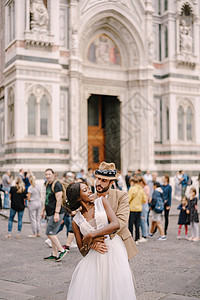意大利佛罗伦萨的婚礼 白人新郎在杜奥莫广场的美籍黑人新娘后面拥抱着她 她很可爱图片