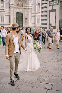 意大利佛罗伦萨的婚礼 非裔美籍新娘和白人新郎沿杜奥莫广场行走 在德杜奥莫广场散步图片