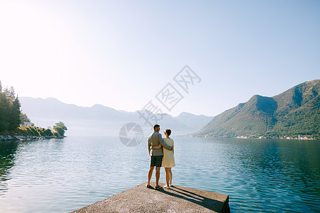 相爱的一对情侣站在Perast附近的Kotor湾的一个码头上拥抱着山背面图片
