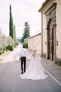 美丽的新娘和新郎手牵手 远离意大利老别墅外面的照相机 在佛罗伦萨附近的托斯卡纳(Toscanne)图片