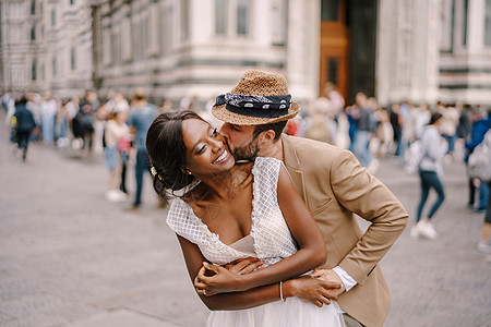 意大利佛罗伦萨的婚礼 白人新郎从背后拥抱并亲吻了非裔美国人的新娘 她很可爱图片