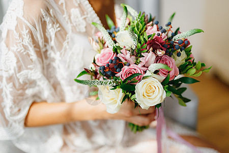 一位穿着白色蕾丝花边的新娘在酒店房间里手里拿着一束婚礼花束 同时为婚礼做准备手指丝带花朵美甲荚蒾装饰投标婚姻玫瑰女孩图片