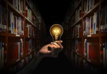 手拿着一个灯泡与图书馆背景中的书架 概念阅读书籍知识和寻找新想法的想法图片