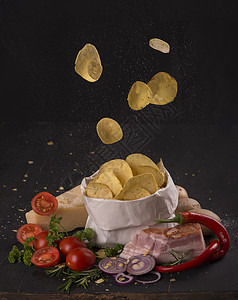 黑木板上的马铃薯片 快餐 黑暗背景美食芯片午餐食物土豆篮子营养油炸香料桌子图片