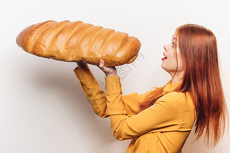 身穿黄色衬衫 手拿着大面包的女子 面粉产品光背景幸福食物面包工作室成人微笑快乐午餐摄影手指图片