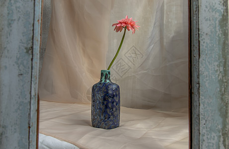 蓝色手工陶瓷花瓶中的粉红色花朵 在腮红纹理桌布上植物群家具礼物陶器热情织物风格制品材料手工业图片