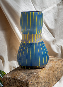 黄色家居白色纹理桌布上的蓝色和黄色手工陶瓷花瓶作品手工业艺术餐具陶器风格装饰热情材料织物背景