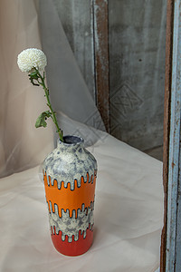 橙色和红色手工陶瓷花瓶中的白花 在腮红纹理桌布上艺术植物群餐具手工业制品礼物材料橙子作品风格图片