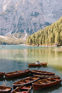 新婚夫妇在意大利的乘坐木船航行 新婚夫妇在欧洲 在多洛米蒂山的布雷斯湖上 新郎划桨 新娘坐在他对面情绪裙子婚姻假期景色奢华幸福恋图片