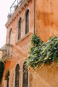意大利威尼斯的古建筑 特写 桃色的墙壁 带木百叶窗的经典威尼斯拱形窗户 带锻造金属格栅的小阳台图片