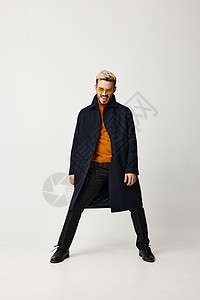 穿着大衣的时装男子将双腿伸在浅背景和橙色毛裤鞋上图片