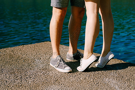 一个男人和一个女人穿着运动鞋的腿站在码头的特写镜头上互相拥抱 一个女人踮着脚尖站着图片