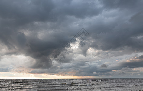 海上日落时阴暗的乌云反射戏剧性阳光海洋太阳雨云地平线蓝色天空天气图片