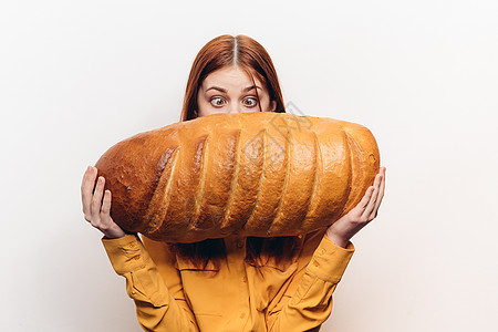 一位幸福的女士 手拿着一包面包 一个在光背景上水平姿势的面包图片