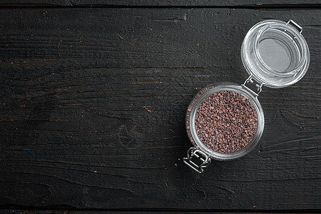 印度黑盐 健康食品概念 在玻璃罐中 在黑色木质背景上 顶视图平躺 带有复制空间和文本空间图片