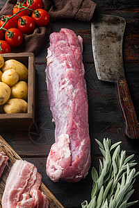土豆肉生猪皮 配有烘烤用原料和草药 圣种 土豆和老屠宰刀刀 旧黑木制餐桌底背景