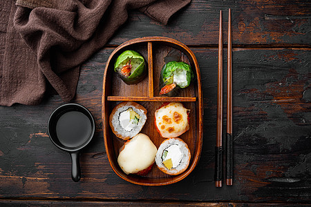 带寿司卷的自制寿司本托盒 在旧黑木桌背景上 顶层视野平铺图片
