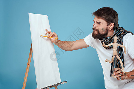 男性艺术家拉衣画画艺术绘画创作蓝背景帆布爱好创造力白色艺术品作坊工艺画笔成人画家图片