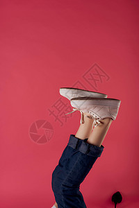 穿白色运动鞋时装工作室粉红色背景的倒转女腿图片