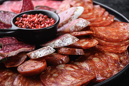 以黑纹本底的巧克力 fuet salami salchichon和Longaniza为原料背景火腿塔帕龙眼熏制食物猪肉香肠小吃白图片