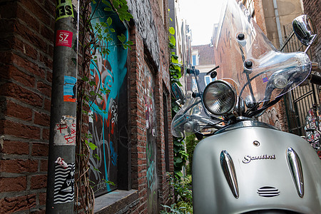 银摩托车停在空砖小巷 墙上涂着涂鸦图片