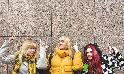 街上的女孩 展示大减价或不错的报价 广告概念 人 旅行和旅游 — 城市街道上的女性用手指在灰色墙壁背景上展示一些东西图片