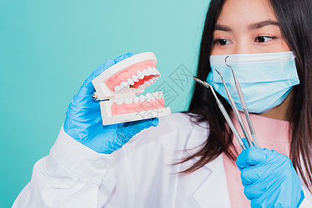 拿着专业工具和模型牙假牙的妇女牙医医生面具药品女士病人技术治疗口腔科外科工作图片