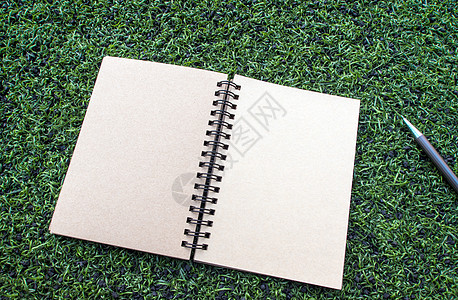 笔印在人工地盘上的纸螺旋笔笔记本空白牛皮纸文档铅笔地毯绿色棕色日记草地草皮图片