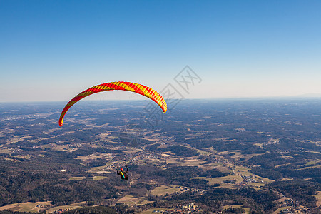 滑翔在乡村上空的降落伞上自由乐趣翅膀风险旅行闲暇飞行员肾上腺素蓝色男人图片