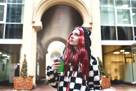 一个穿着暖和衣服的红头发的少女的画像 在寒冷的日子里 她手里拿着一杯咖啡 抬头走到外面 可爱的女孩手里拿着咖啡走路图片
