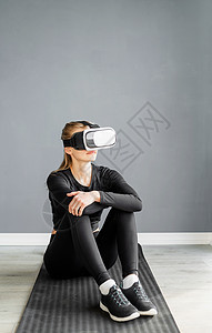 身着运动服 戴着虚拟现实眼镜坐在健身马上的年轻金发女性沉思技术运动员工具模拟活动训练娱乐思维成人图片