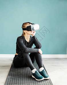 身着运动服 戴着虚拟现实眼镜坐在健身马上的年轻金发女性沉思女士工具思维活动女孩训练娱乐运动成人图片