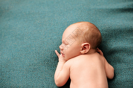 刚出生的婴儿男孩在第一次拍照时 睡在绿松石背景上图片