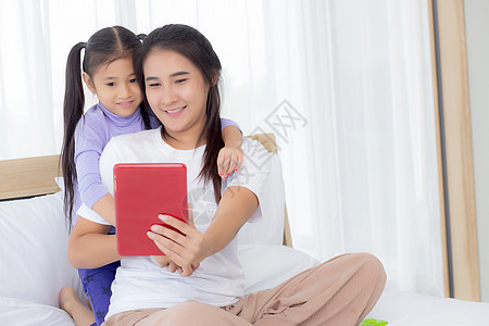 年轻的亚洲妈妈和女儿在平板电脑上视频通话与家人一起问候 快乐的母亲和女孩使用技术与互联网在线交流 两个人乐趣母性女性电话问候语童图片