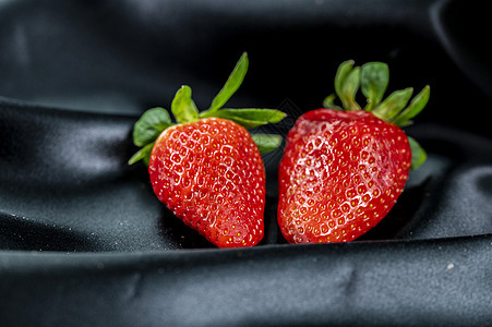 黑沙子布料背景上的成熟草莓图片