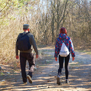 一个男人和一个十几岁的女孩 带着背包走在森林路上 在阳光明媚的后视线上家庭青少年晴天女性自由女士游客假期孩子冒险图片