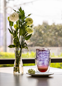 一杯加柠檬水的苏打饮料 橙汁搅拌器蝴蝶豌豆汁 (Anchan) 冷清爽饮料或加冰的饮料 一束白玫瑰放在白色桌子上的玻璃花瓶里图片