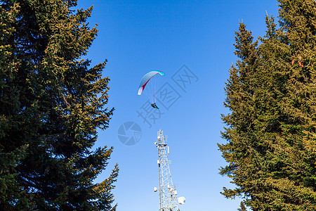 滑翔在乡村上空的降落伞上蓝色行动假期自由男人冒险航班活动山脉肾上腺素图片
