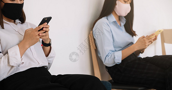 两名亚洲年轻女性在智能手机上聊天并戴面罩 远离COVID19病毒保护社会疏远以防范感染风险口罩面具视频流感疾病安全技术团体同事女图片