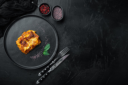 带有奶酪贝查梅尔和布洛涅司酱的经典肉意大利面条 在盘上 黑石背景 顶层视图 平地 文字复制空间图片