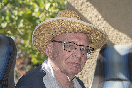 老爷爷戴眼镜和草帽 在阳光明媚的秋天 看着摄影机衬衫白色退休祖父母医学灰色商业帽子老年男性图片