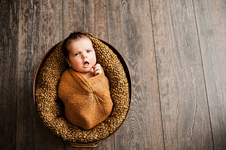 身着棕色包裹的女婴在新生儿照相机上打哈哈哈哈哈哈图片